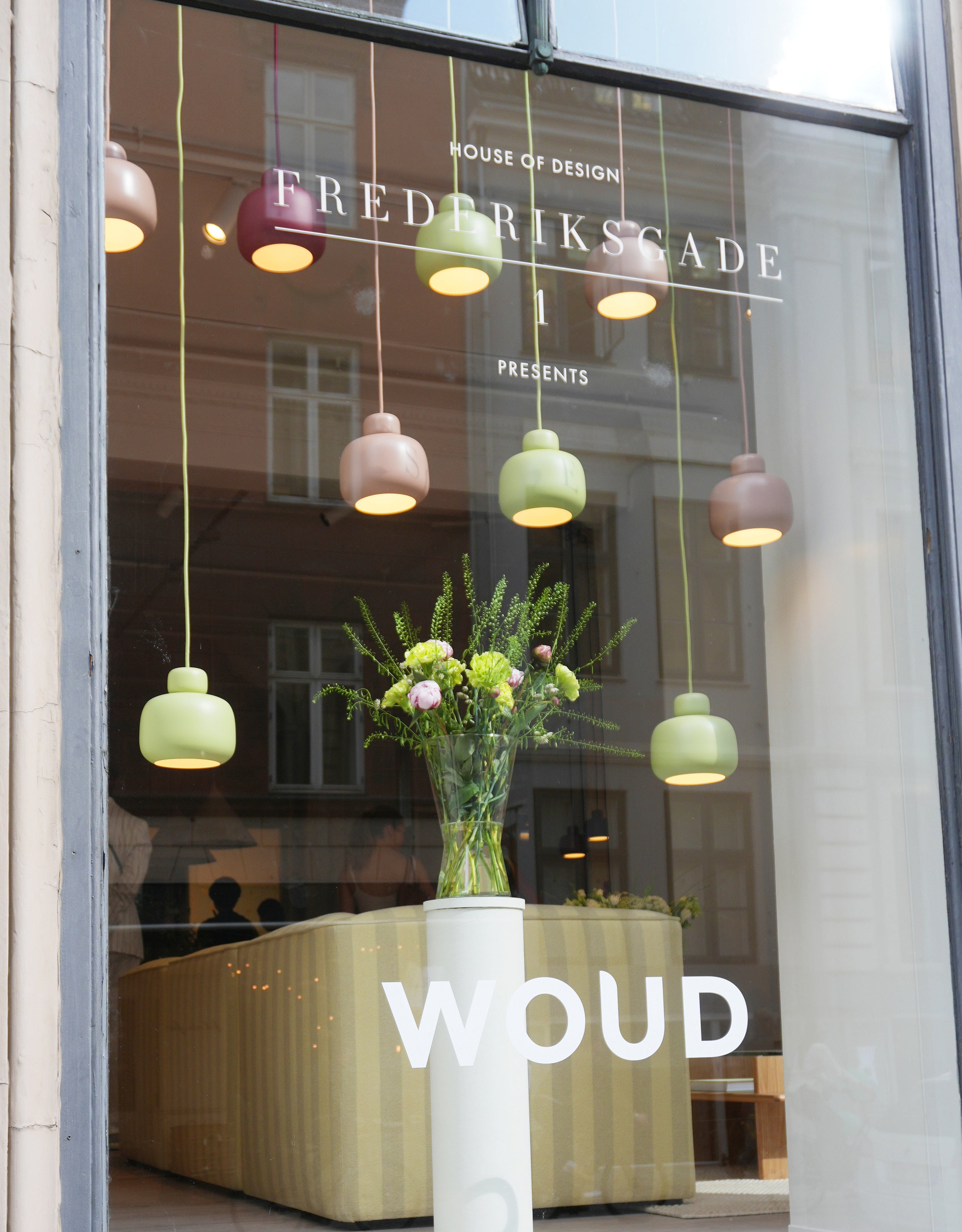 Klynge af farverige lamper i skandinavisk design set gennem vindue udefra.