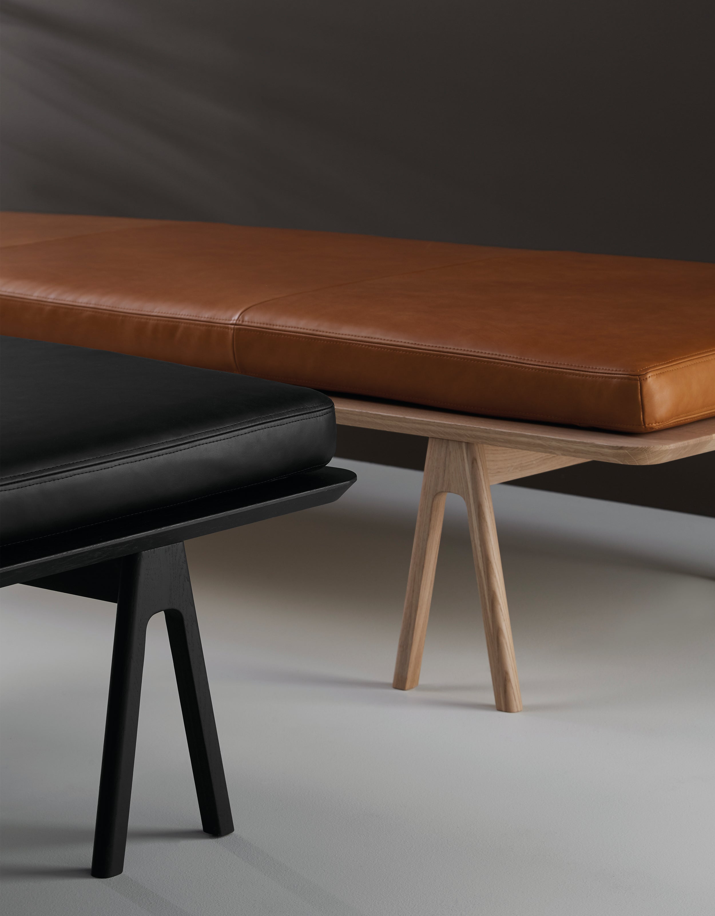 Close-up af to daybeds, en egetræs daybed med cognac lædermadras, og en sort daybed med sort lædermadras