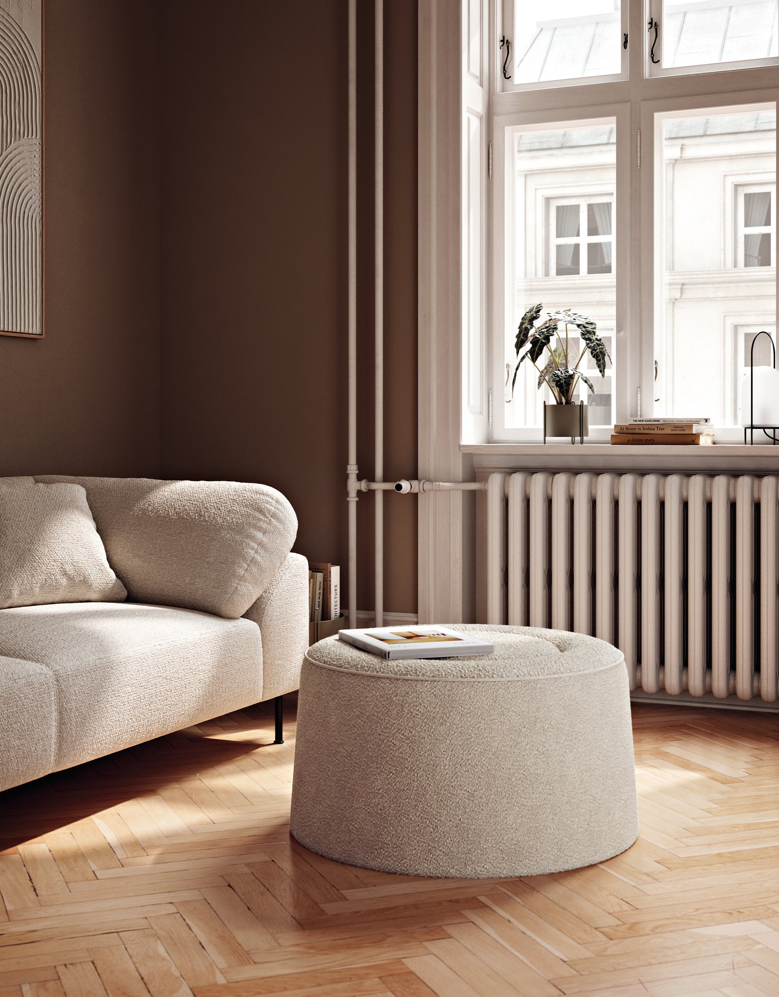 Rund beige pouf placeret foran sofa i skandinavisk indrettet stue.