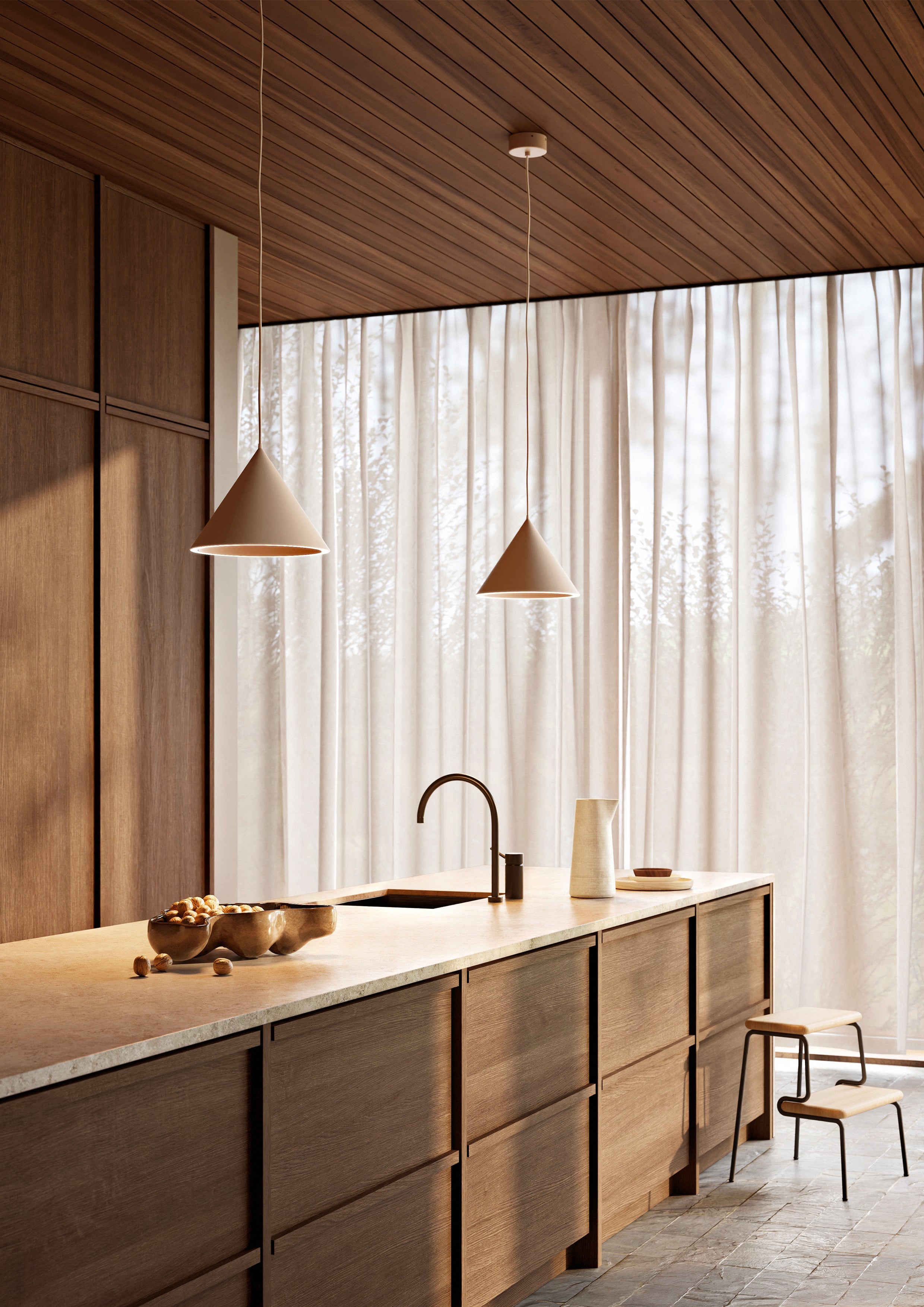 To beige pendler over køkkenø med mørke trælåger og råhvid bordplade.