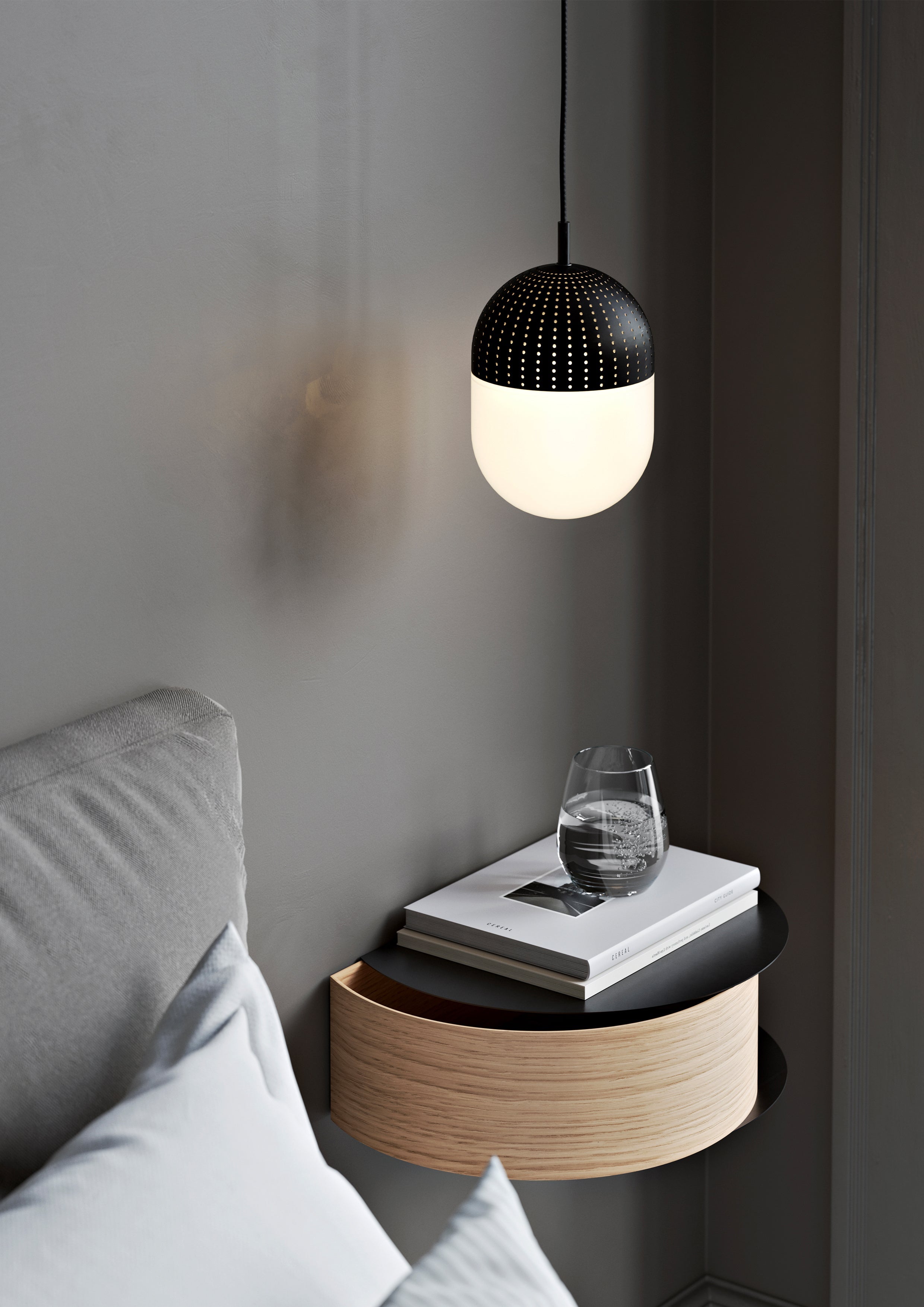 Pendel med opalglasskærm og perforeret metal over væghængt egetræs hylde i soveværelse ved siden af sengen.