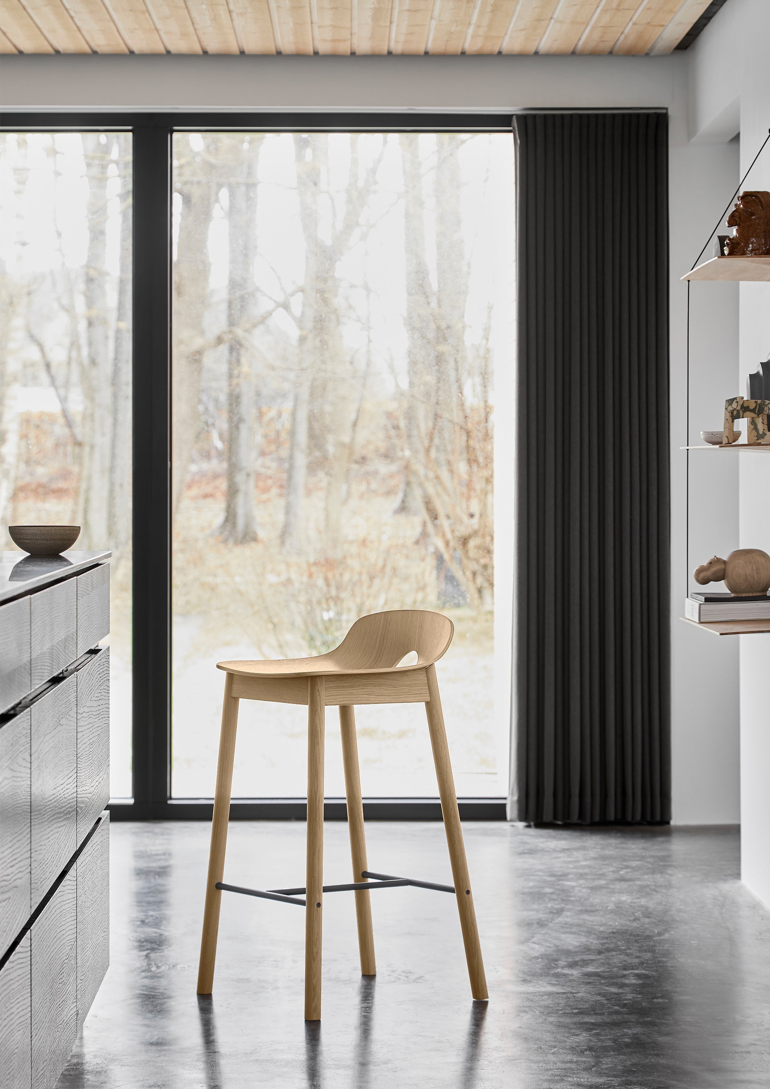 Hvidpigmenteret egetræs barstol i skandinavisk design i køkken med naturligt lys fra store vinduer.