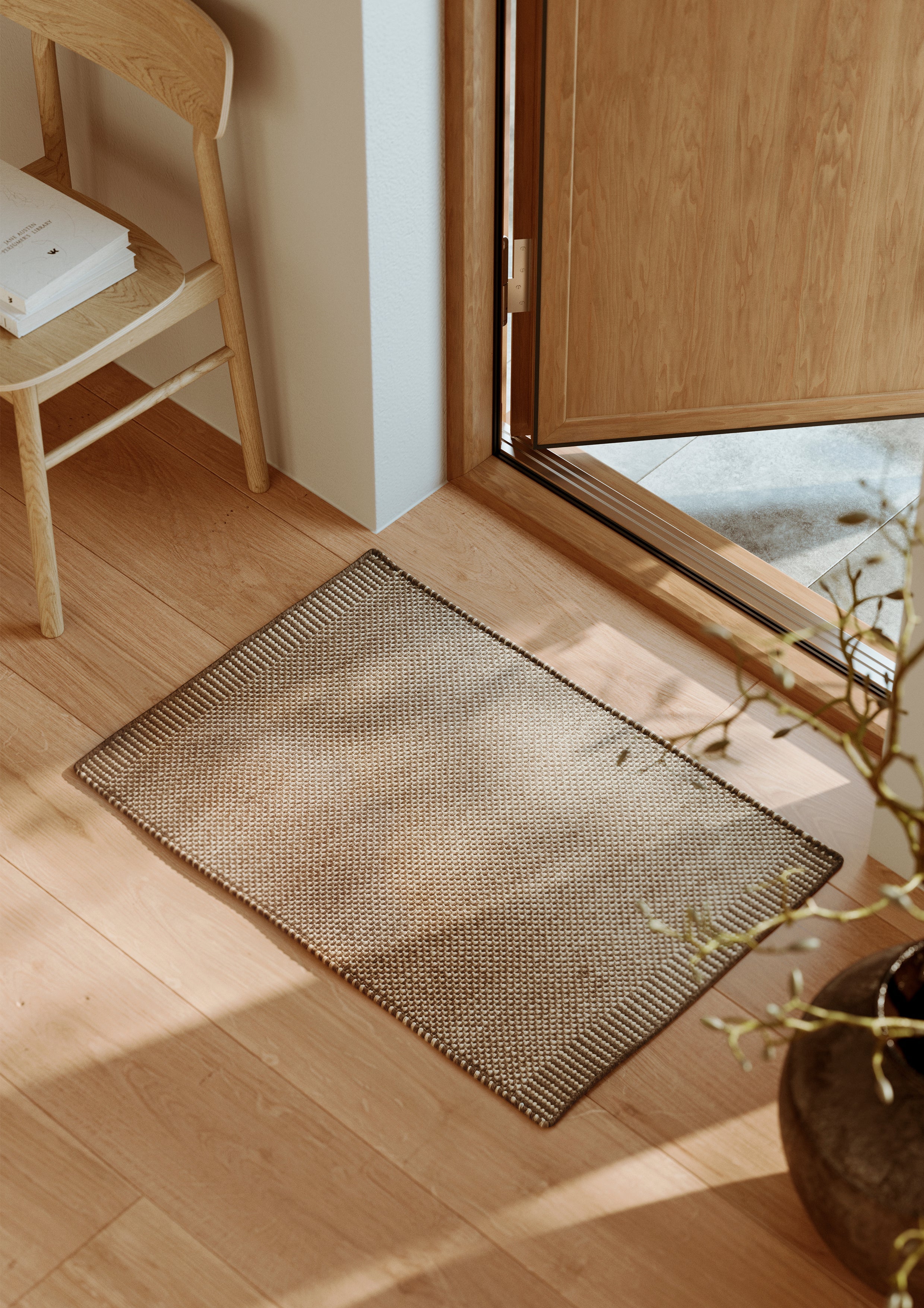run håndvævet dørmåtte foran åben dør belyst af naturligt sollys.