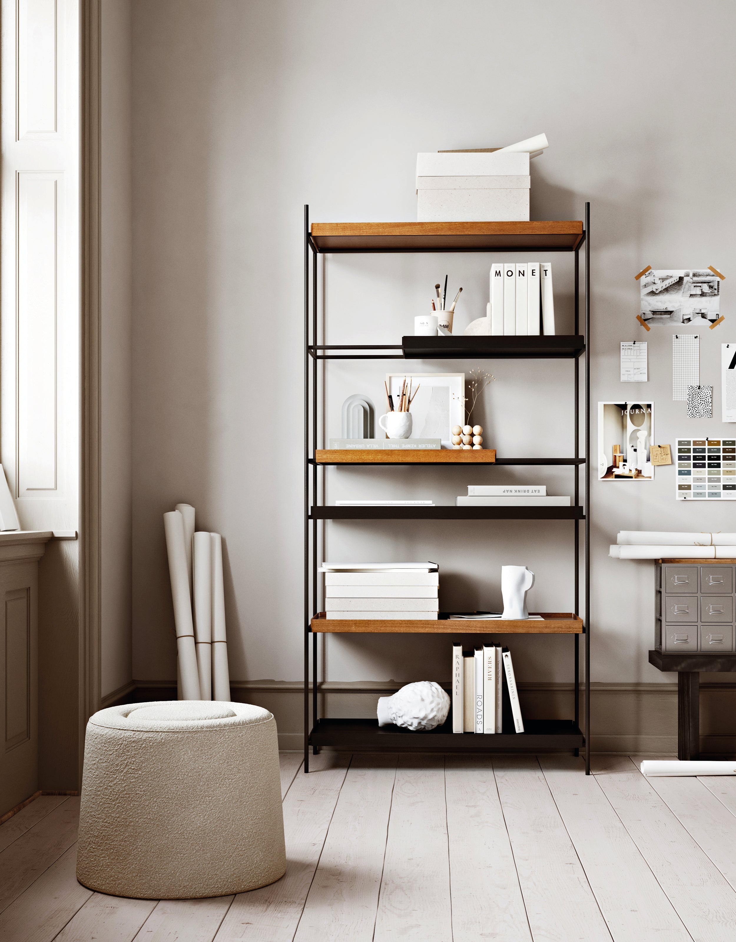 Åbent reolsystem med sort metalramme og hylder i sort og valnød, stående i et kreativt arbejdsmiljø